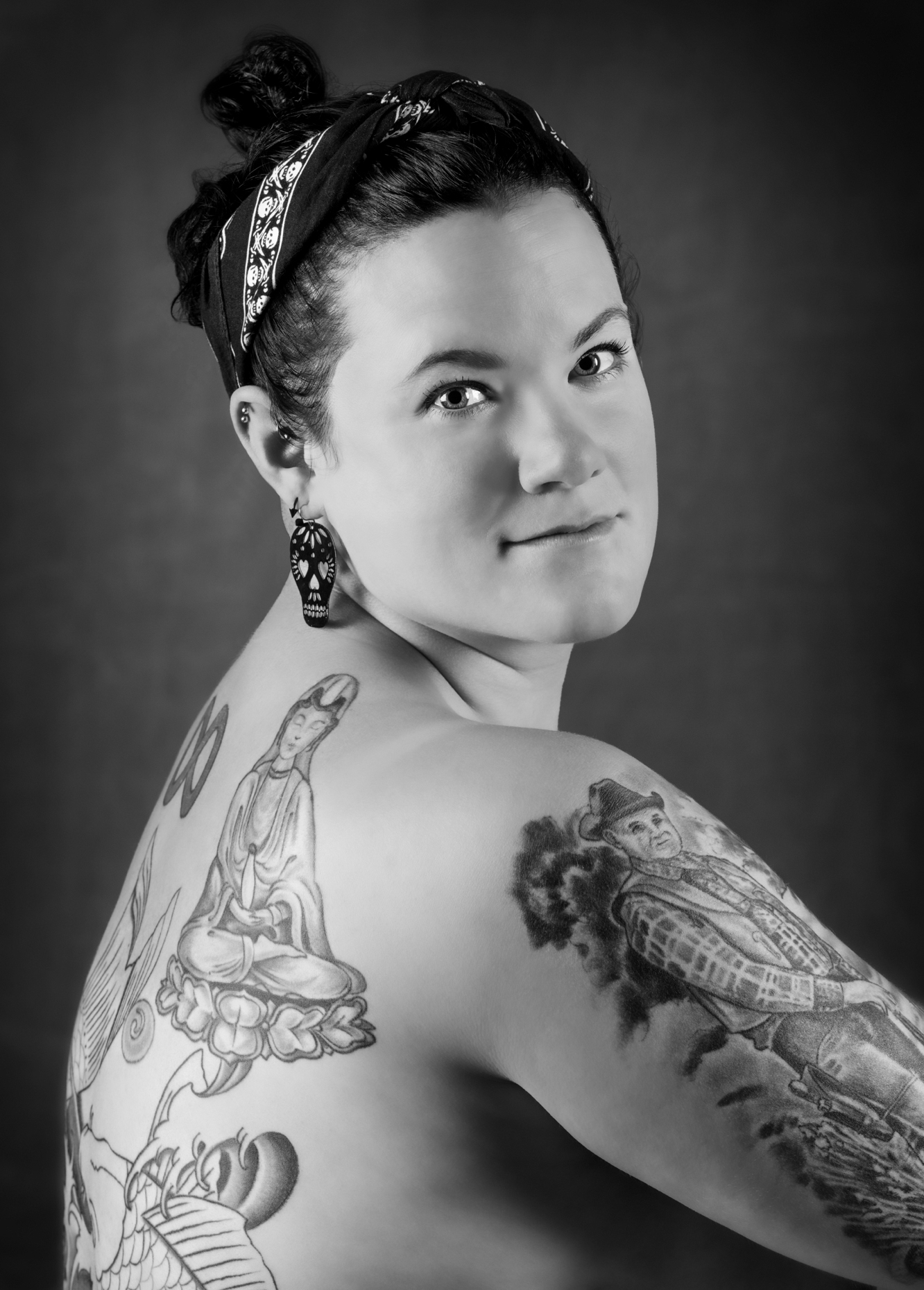 Black & white studio portrait of tattoos on a beautiful young nude woman
