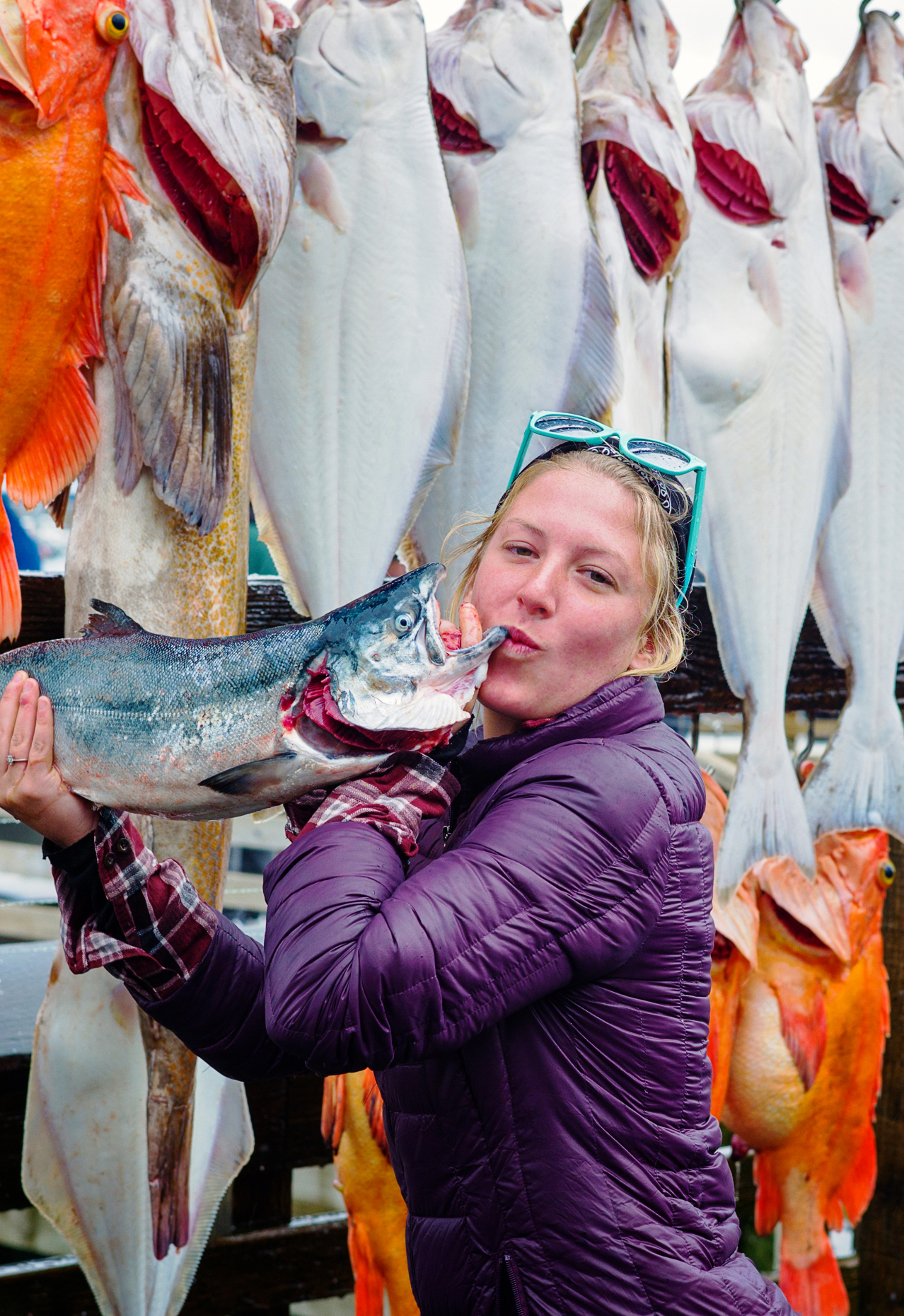 Female fisherman kisses a fish. Charter boat fisherman take photographs of themselves with their fresh catch of the day, Seward, Alaska, USA