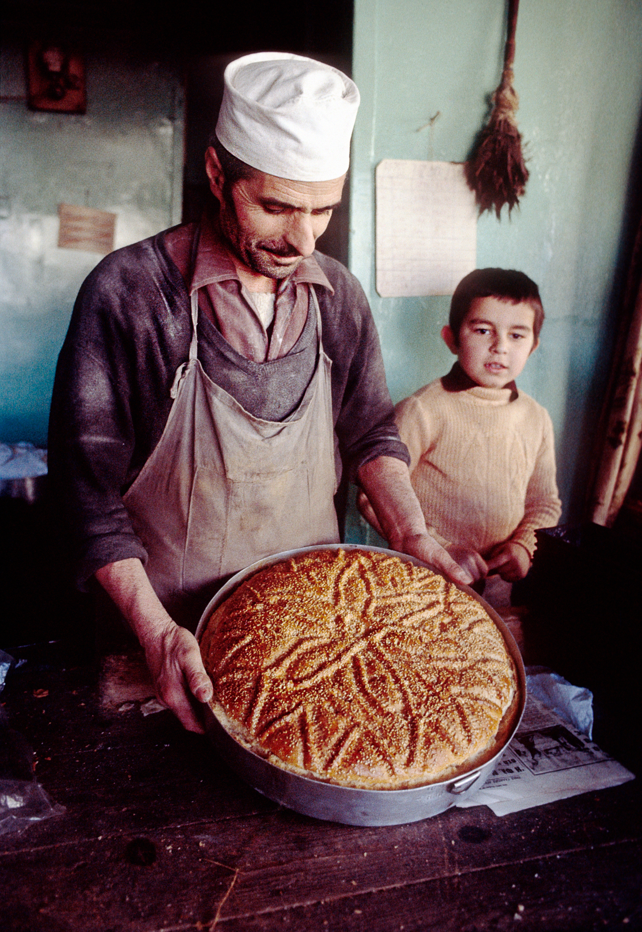 Local Greek baker and son show a freshly baked Christmas bread in the small northern mountain town of Metsovo, Greece