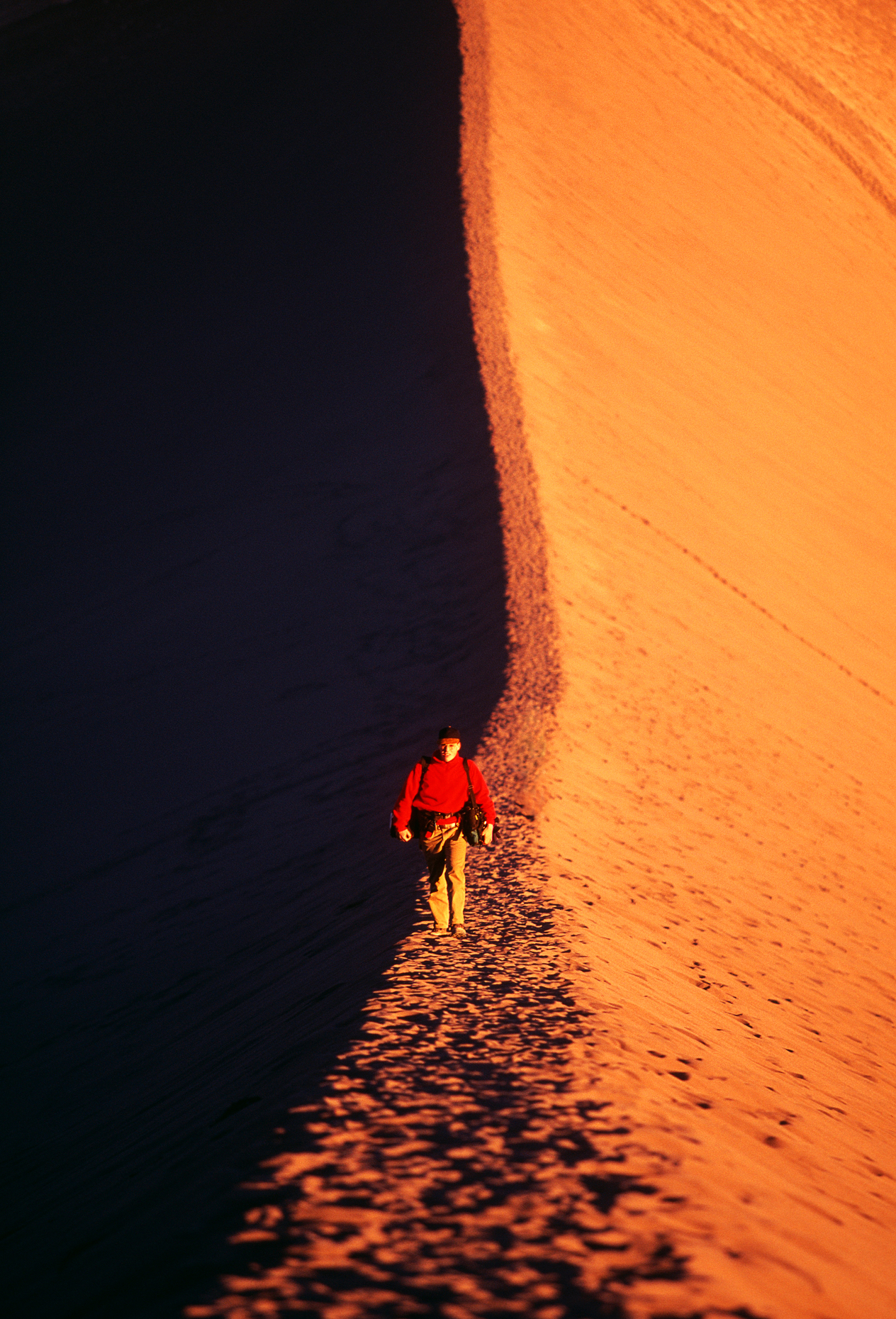 Male hiker walks along the ridge of a sand dune, Valley of the M