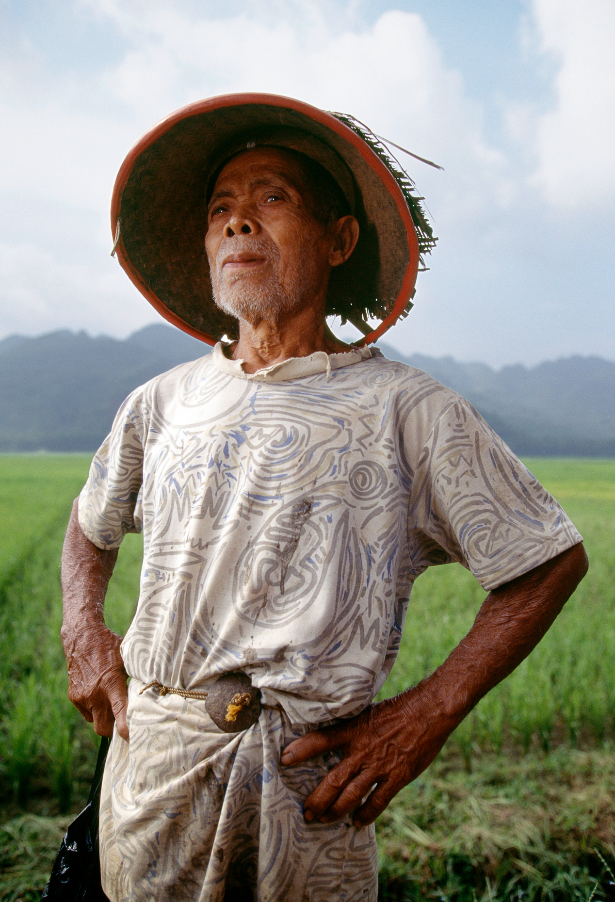 Portrait of elderly Indonesian farmer at his rice paddies betwee