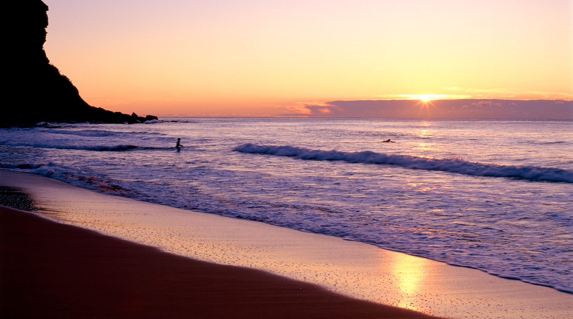 Surfers head out at sunrise at Bungan Beach, New South Wales, Au
