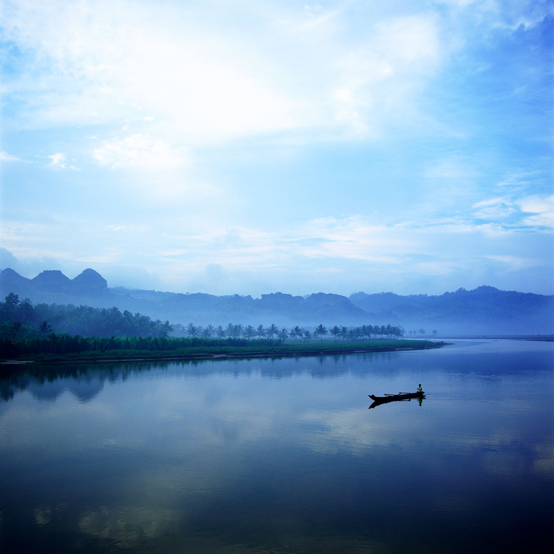 Man in boat on a foggy dawn on the Bodo Ijo River near Ayah, south coast of Java, Indonesia