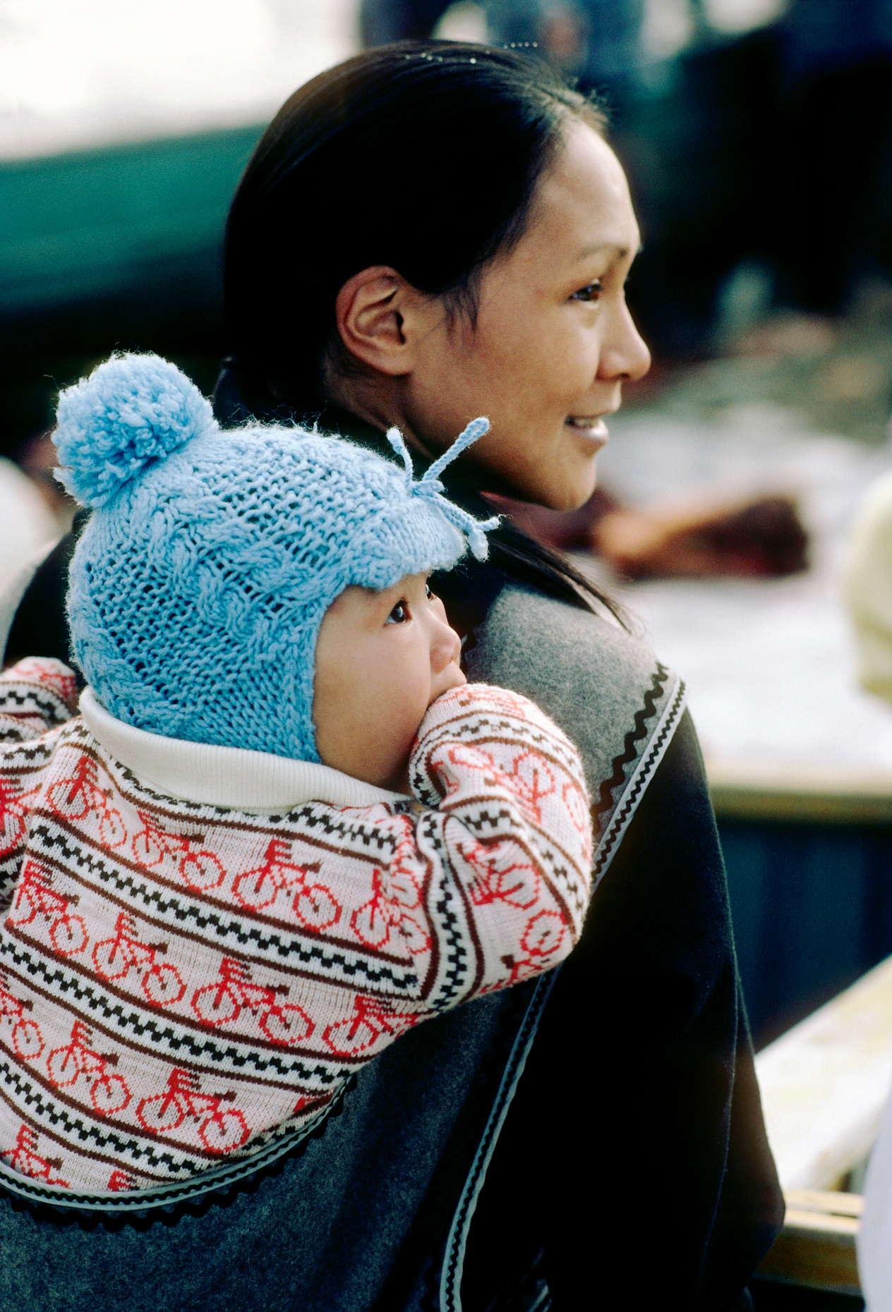 Inuit woman carrying her baby boy in a traditional hood pouch on
