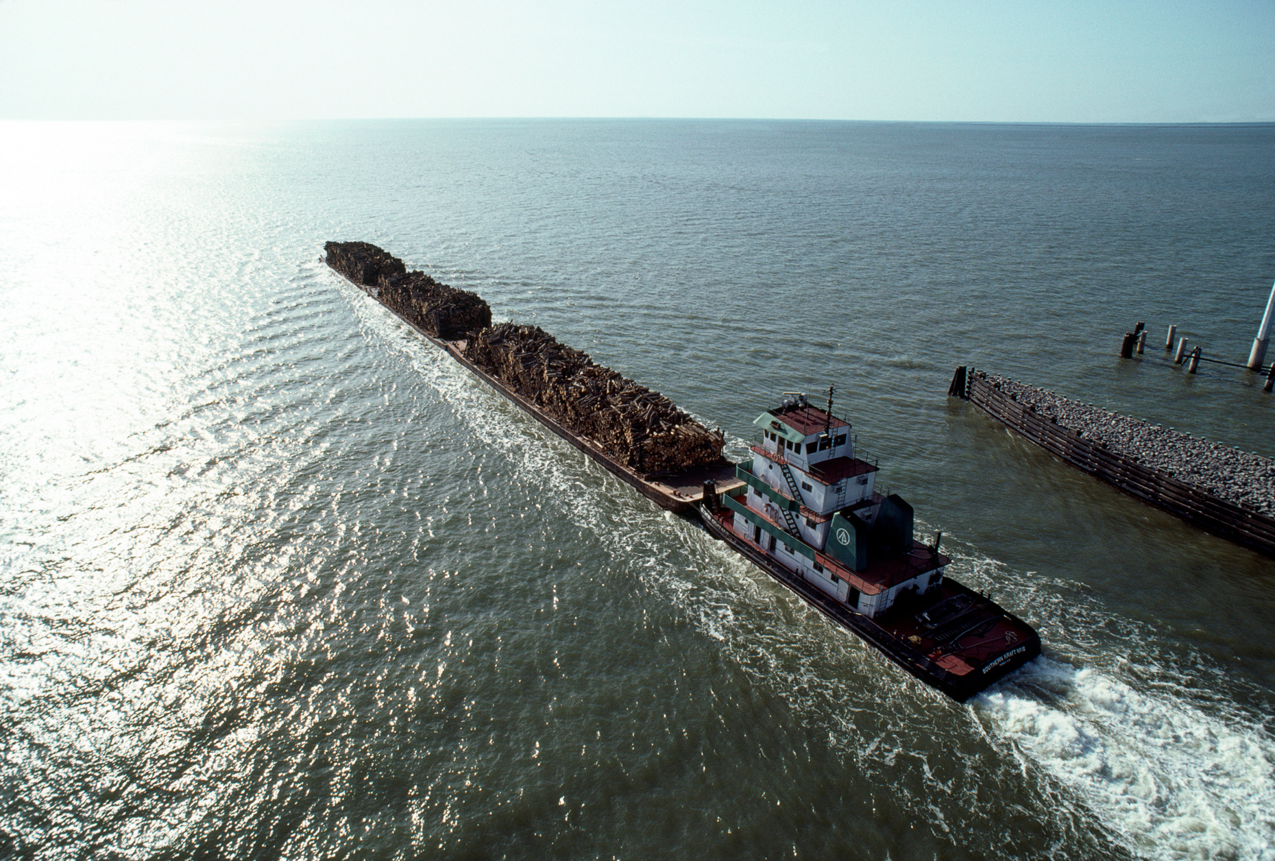 Tug boat pushing barges loaded with logs up the Houston Shipping Channel, Texas, USA