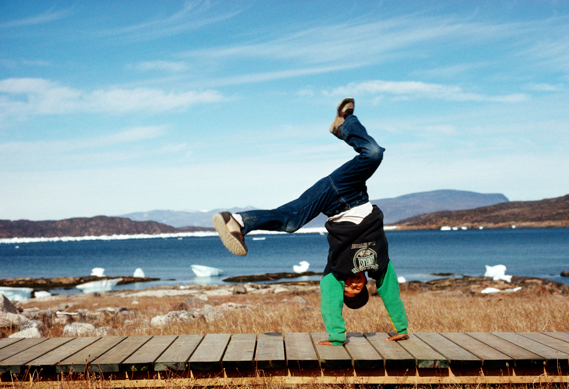 Young Inuit boy does a cartwheel on the boardwalk at historic Ke
