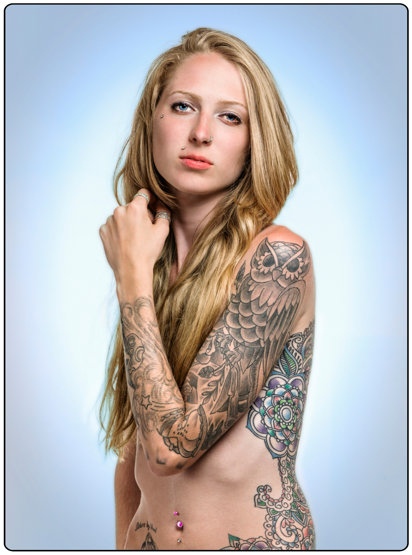 Studio portrait of tattoos & body piercings on an attractive nude blonde haired young woman