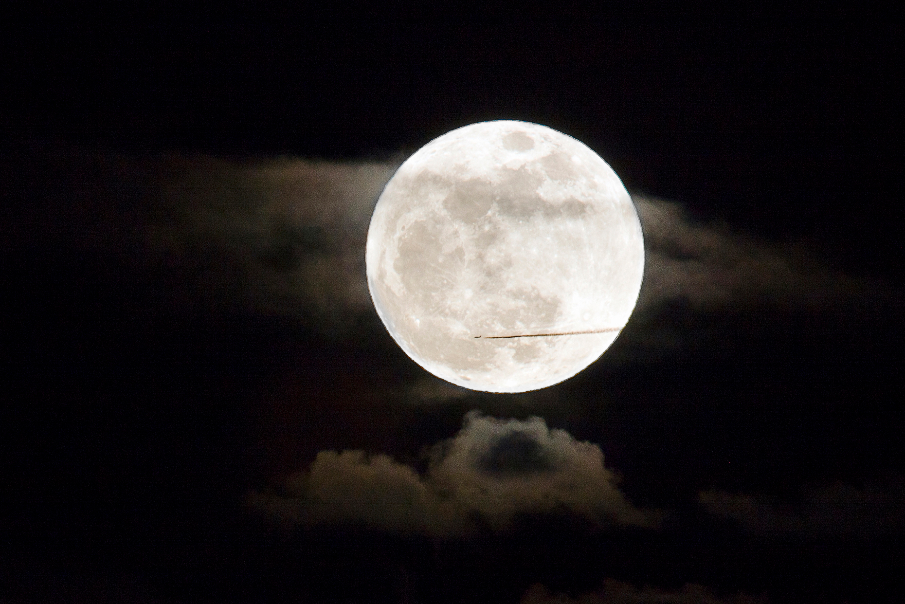 Commercial jet flies in front of a perigree full moon, or supermoon, rising over Salida, Colorado, USA
