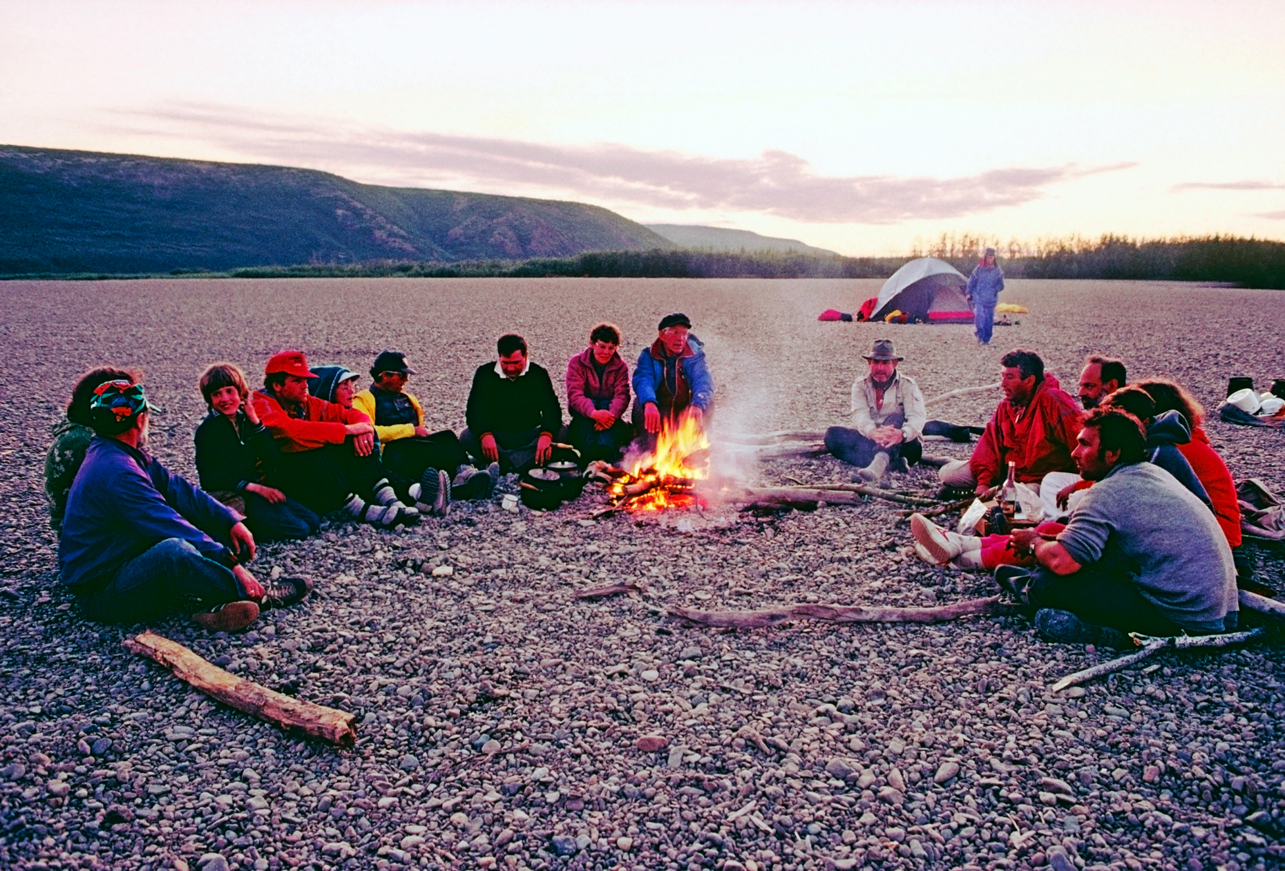American adventure travelers with Soviet guides sit around a campfire, Belaya River, Magadon Region, Siberia, former Soviet Union