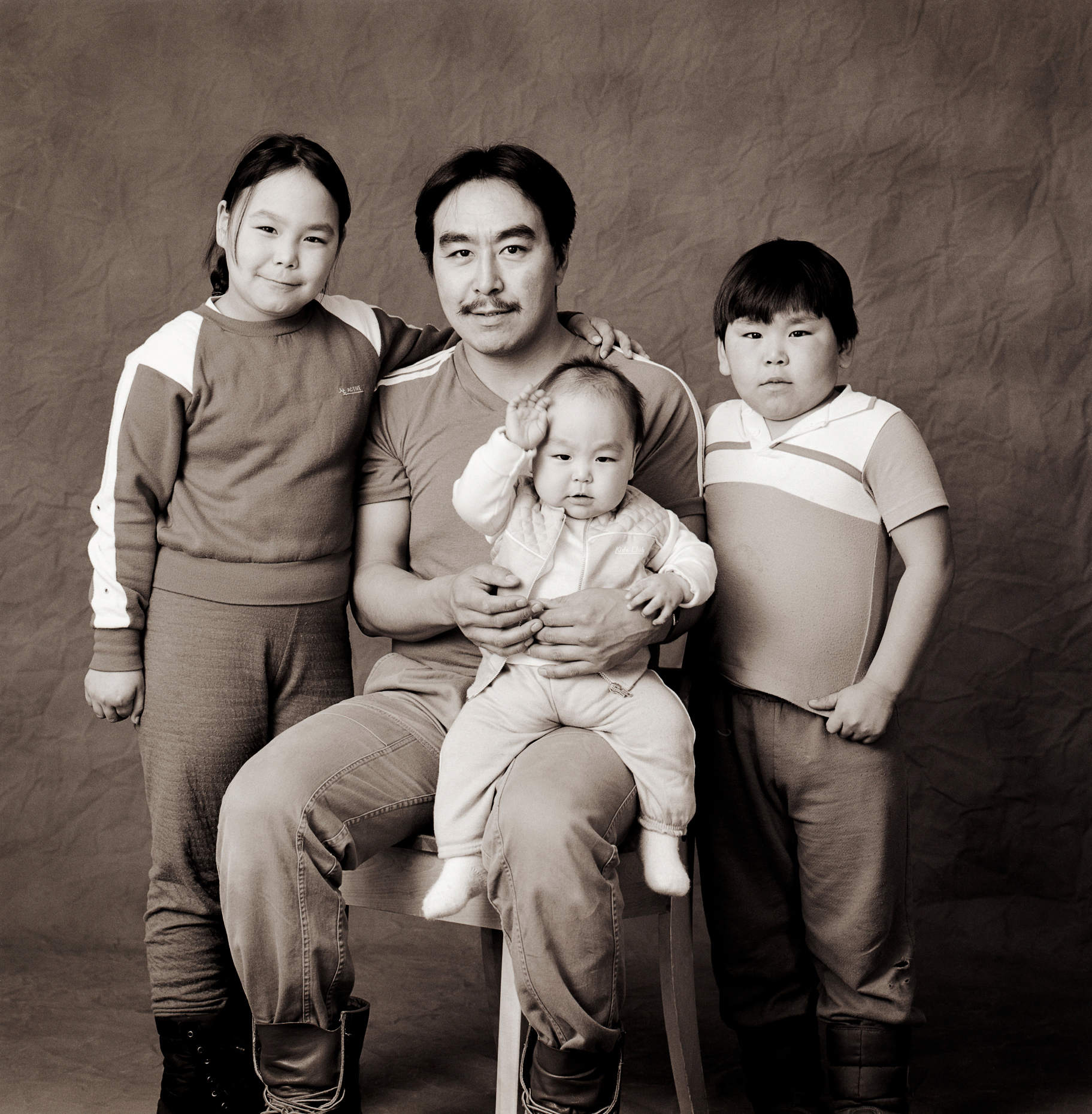 Black & white studio portrait of Inuit father and children in a photography studio in Iqaluit, Nunavut, Canada