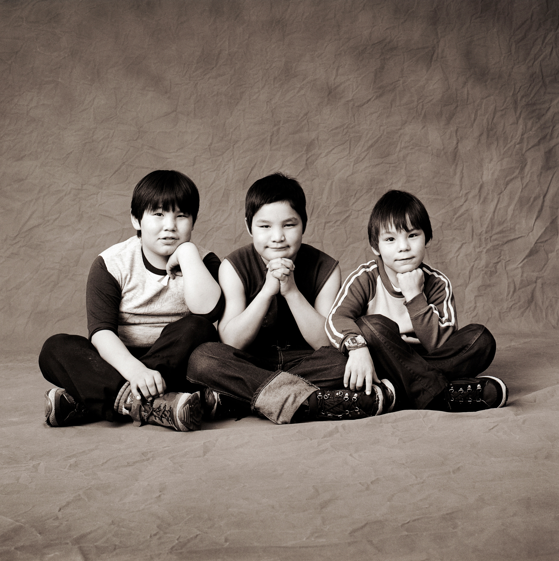 Black & white studio portrait of three Inuit boys in a photography studio in Iqaluit, Nunavut, Canada