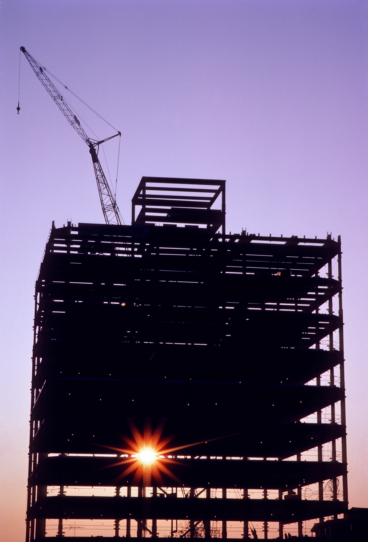 Sunrise through the steel framework and crane for a skyscraper