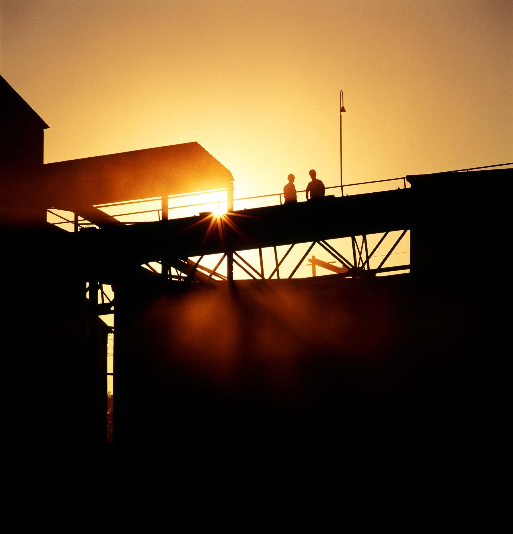 Workers silhoutted against the sunrise at a cement plant.