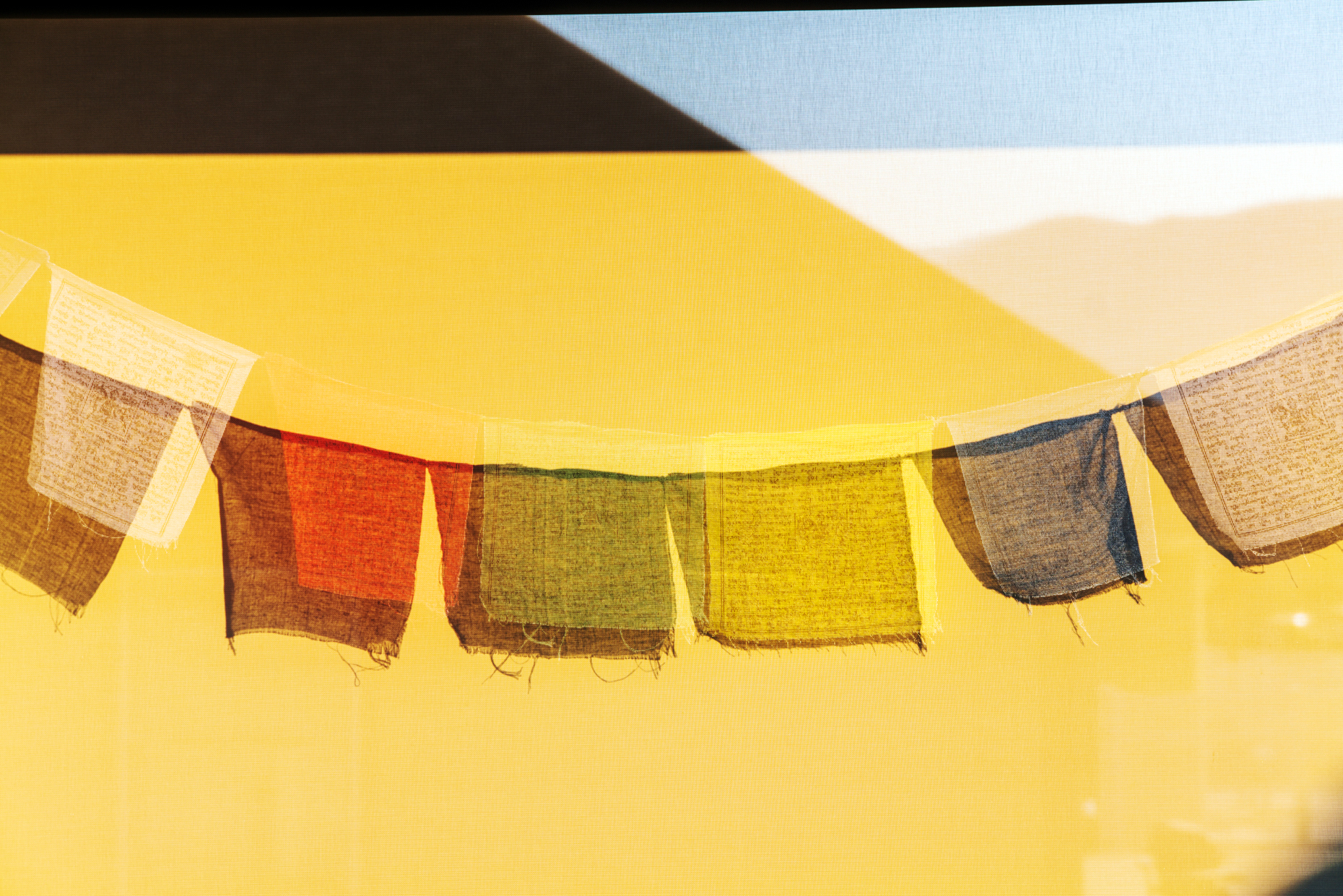 Sun casts shadows of traditional Buddhist prayer flags on a wind screen