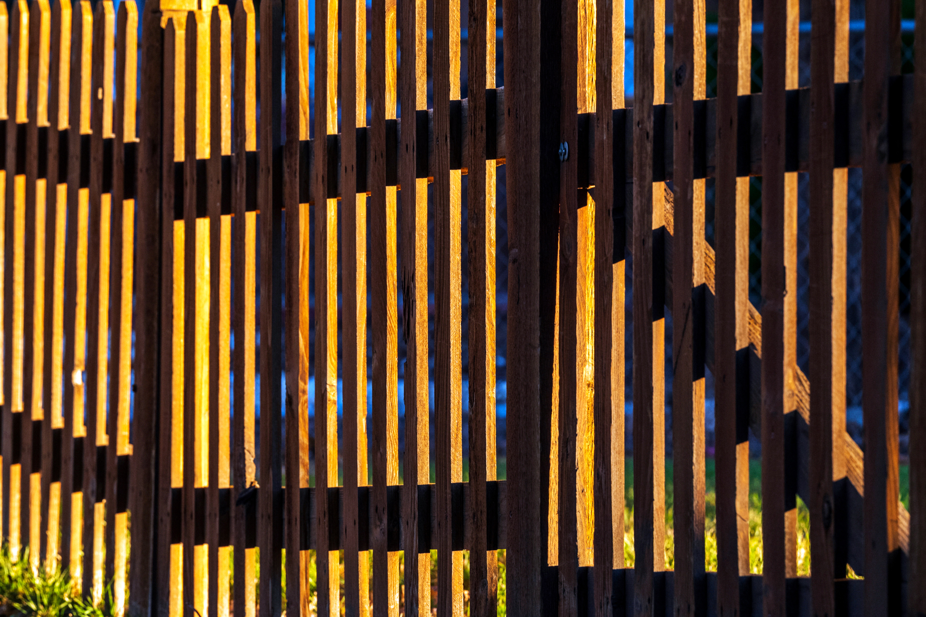 Late day sunlight creates patterns on wooden picket fence; 325 D