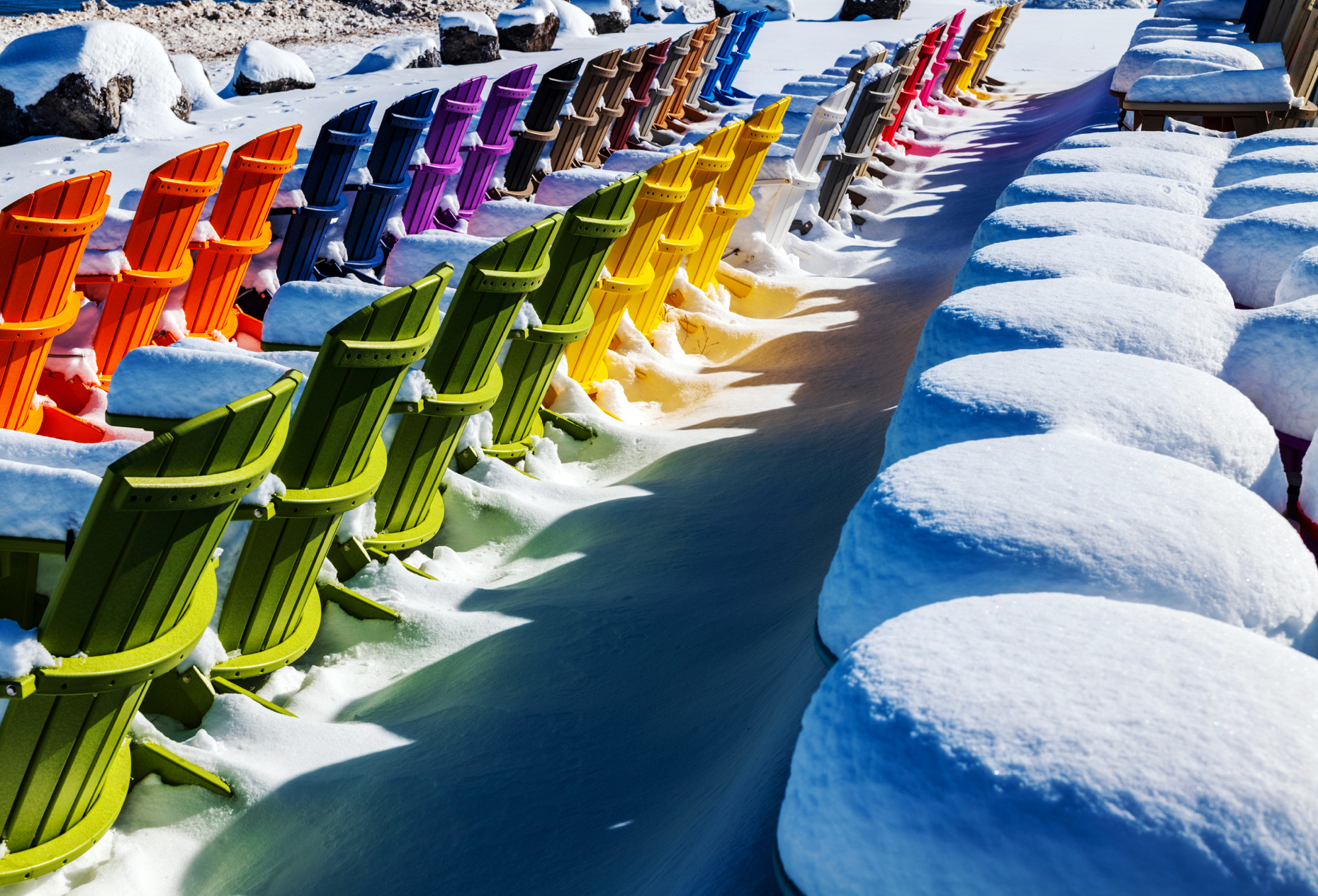 Colorful Adirondack style chairs in fresh snow; retail store; Poncha Springs; Colorado; USA
