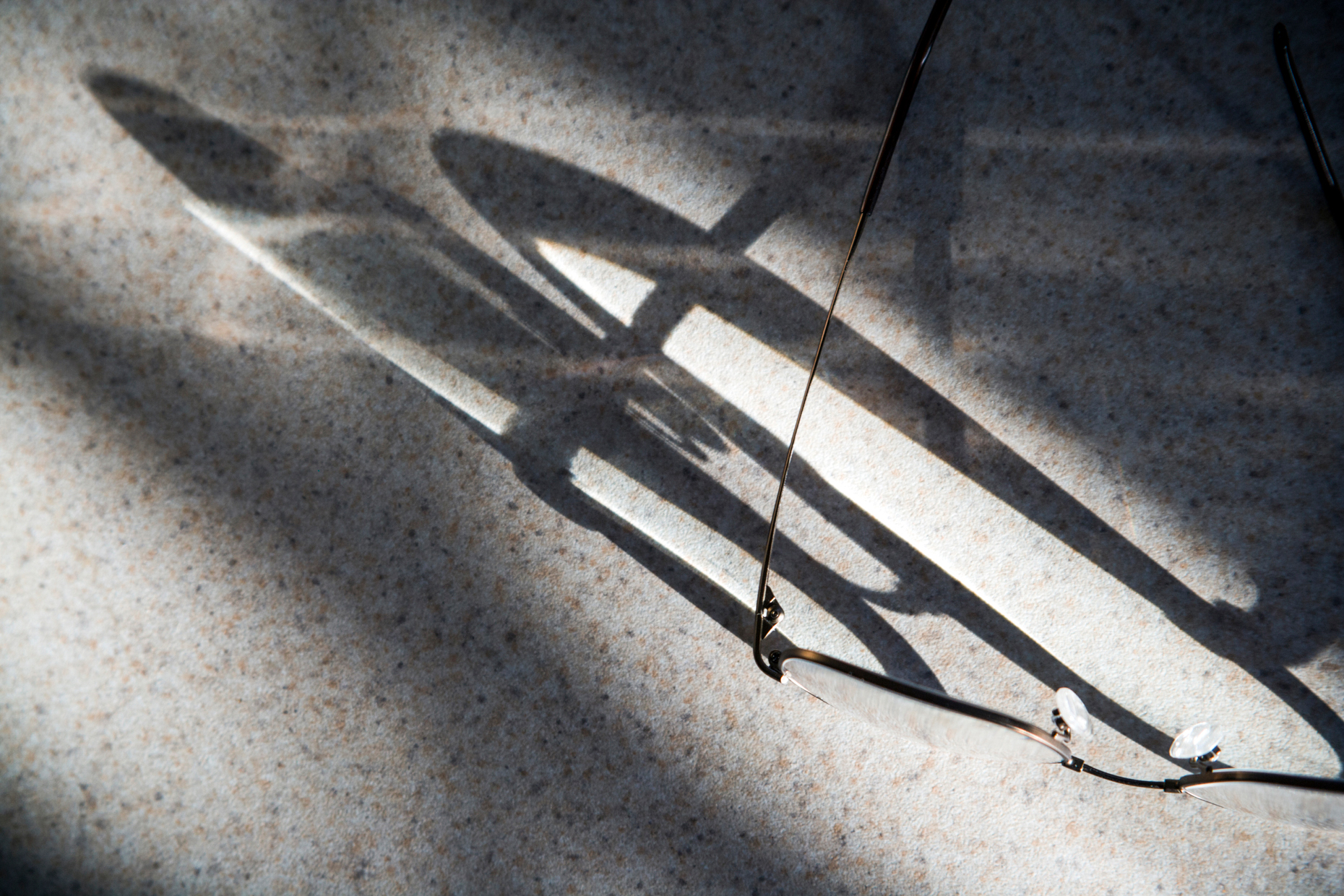 Abstract view of shadows cast by sunlight on reading glasses