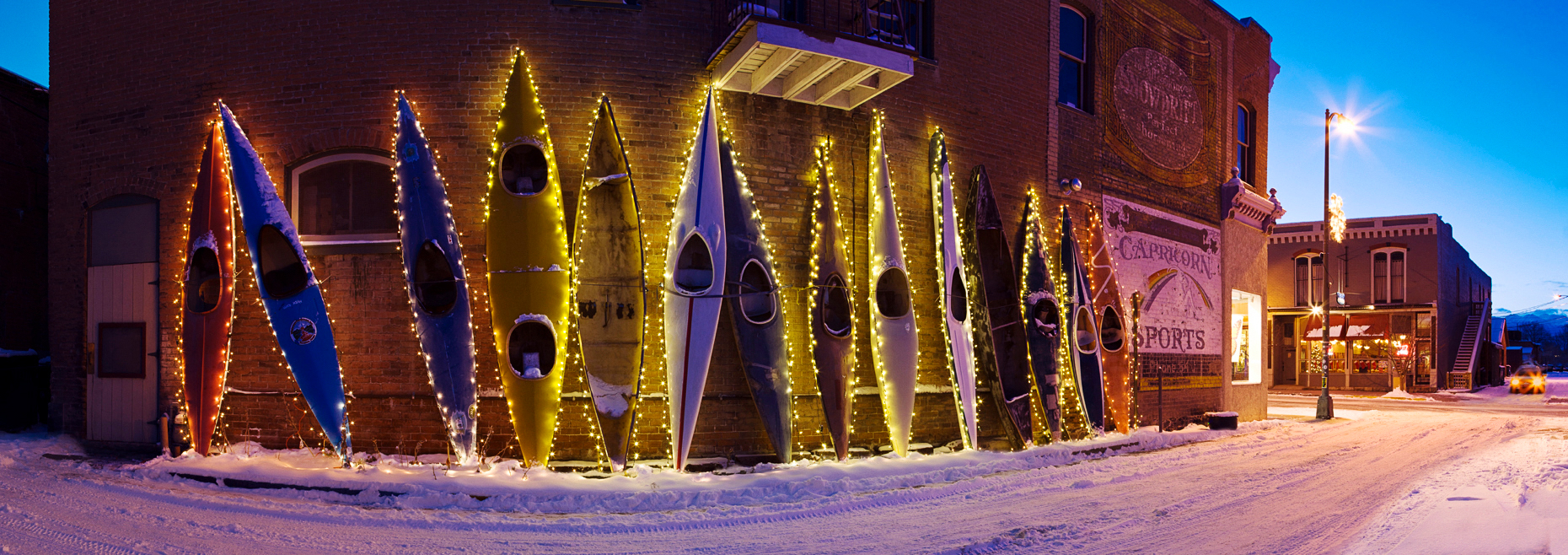 Dusk view of holiday lights illuminate colorful kayaks along a historic building in downtown Salida, Colorado, USA.