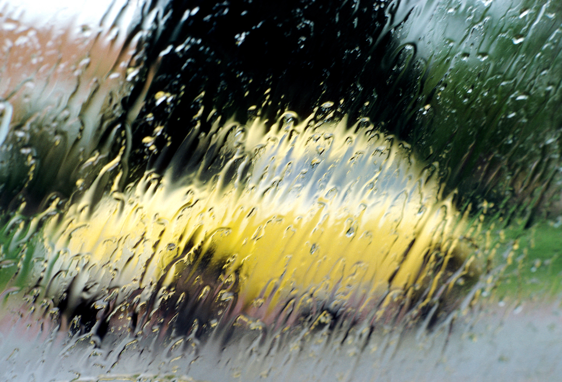 Yellow Volkswagon Beetle in the rain viewed through the windshie