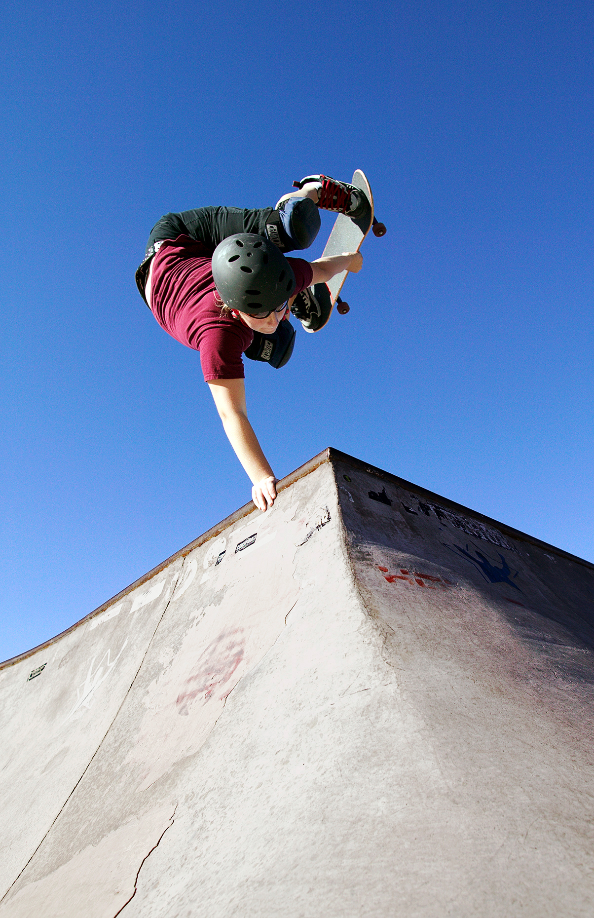 Female teenage girl performs tricks in a skateboard park.